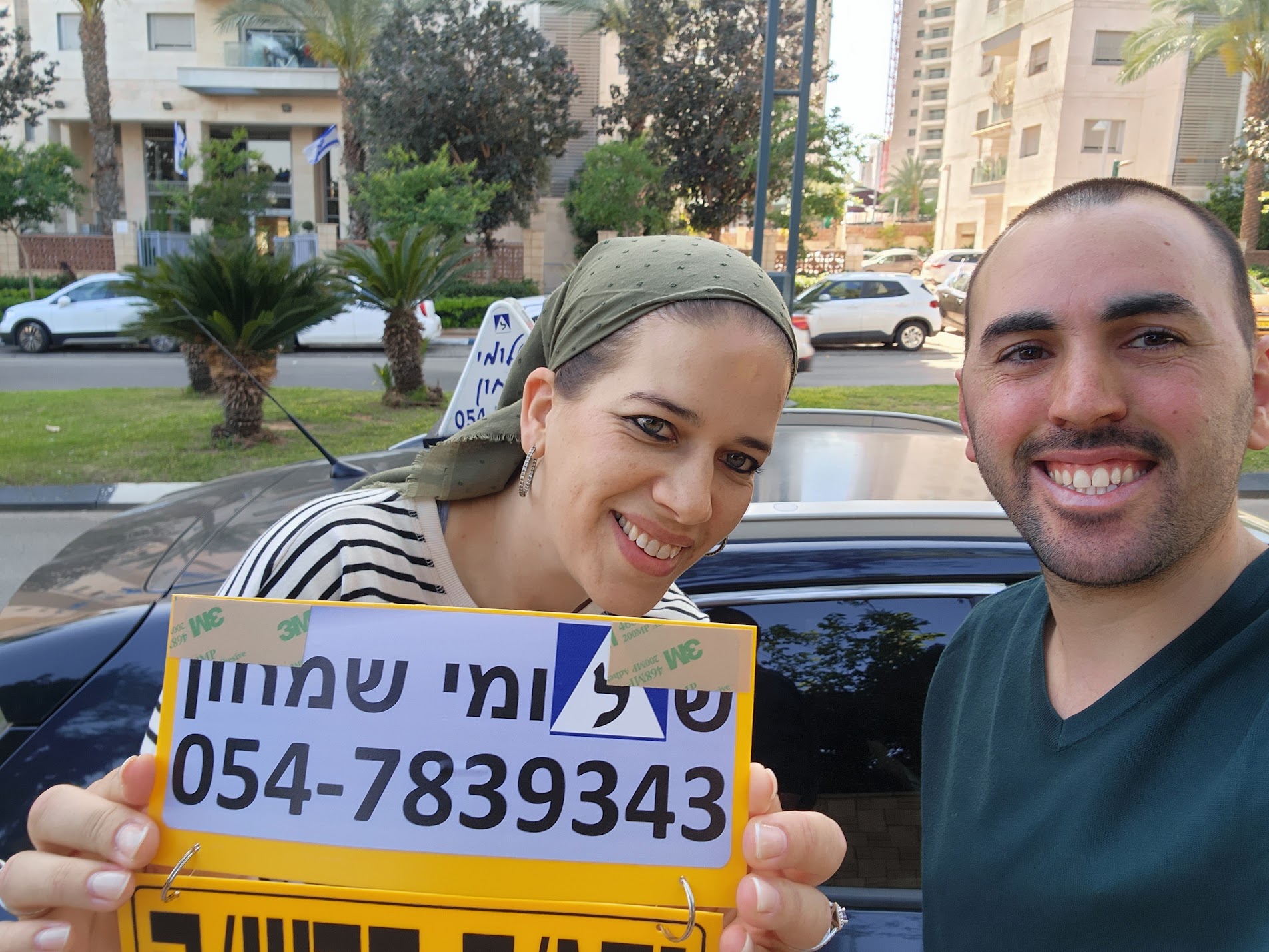 תלמיד עם שלומי שמחון, מורה נהיגה, מחזיק שלט "נהג חדש" לאחר המבחן – תמונה 52