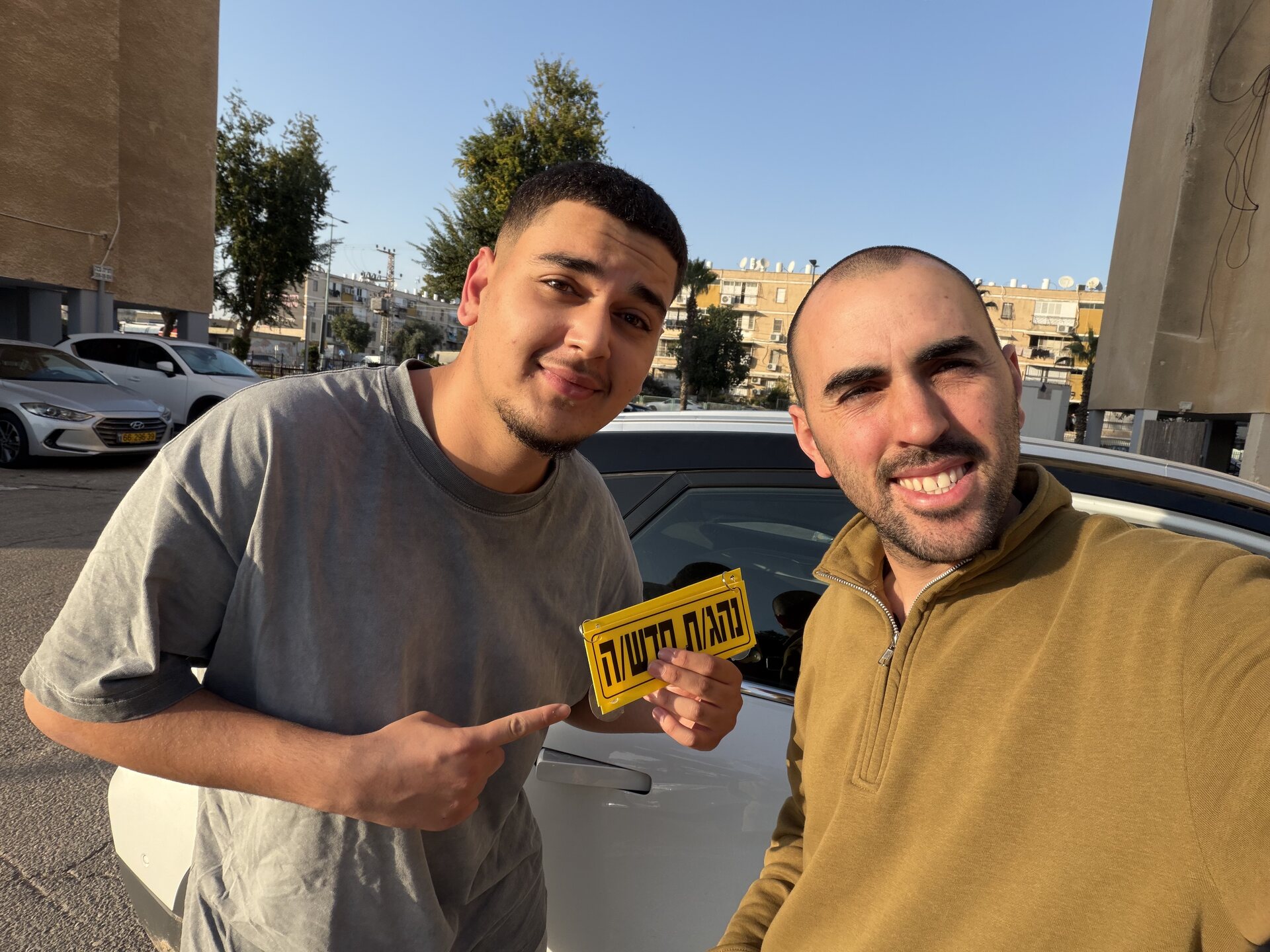 תלמיד עם שלומי שמחון, מורה נהיגה, מחזיק שלט "נהג חדש" לאחר המבחן – תמונה 60