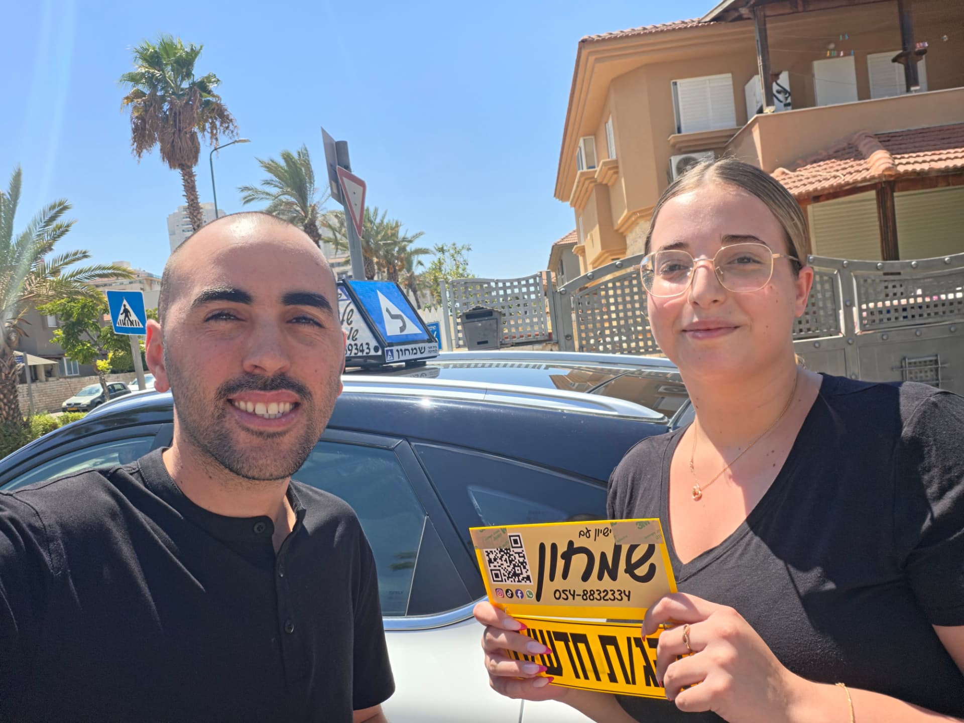 תלמיד עם שלומי שמחון, מורה נהיגה, מחזיק שלט "נהג חדש" לאחר המבחן – תמונה 12