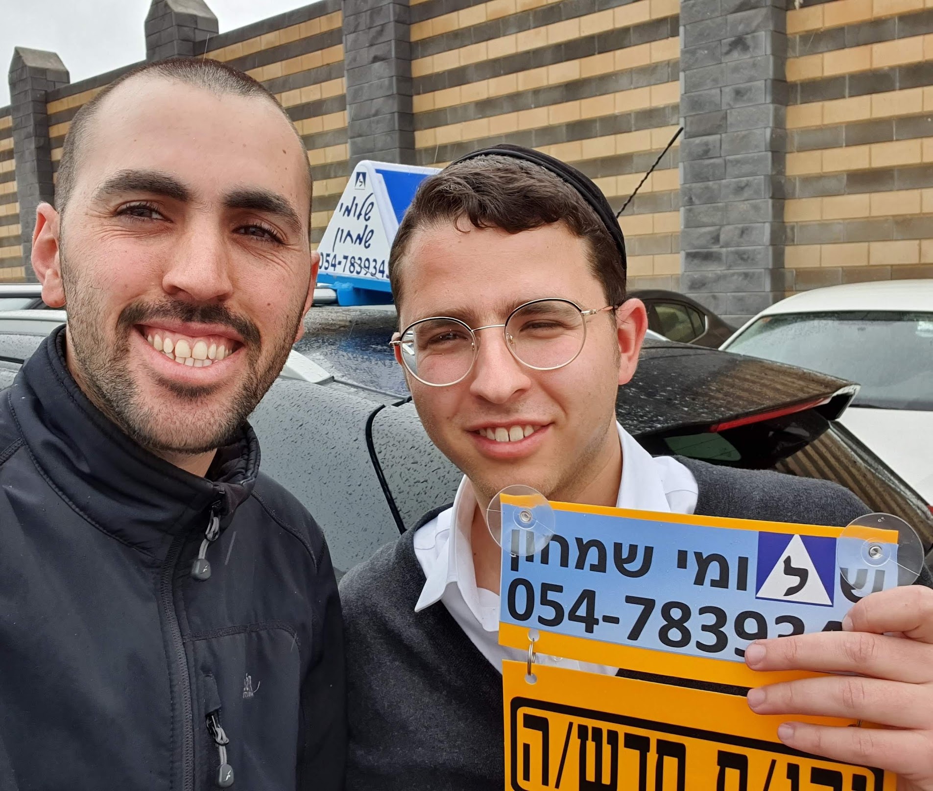 תלמיד עם שלומי שמחון, מורה נהיגה, מחזיק שלט "נהג חדש" לאחר המבחן – תמונה 4