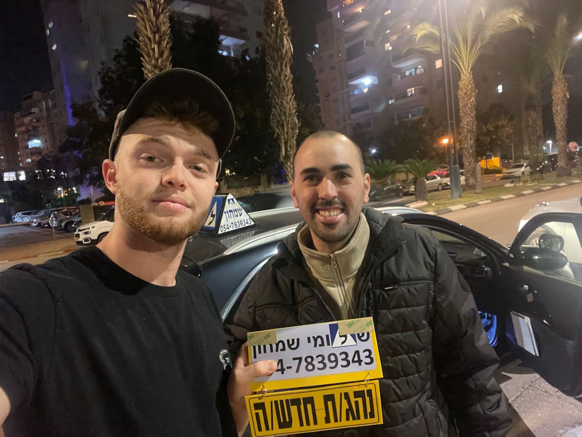 תלמיד עם שלומי שמחון, מורה נהיגה, מחזיק שלט "נהג חדש" לאחר המבחן – תמונה 53