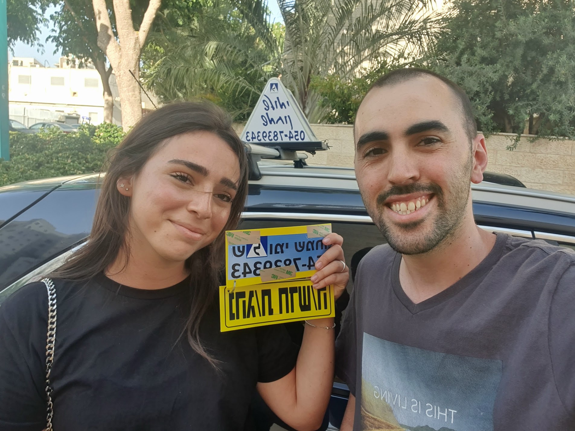 תלמיד עם שלומי שמחון, מורה נהיגה, מחזיק שלט "נהג חדש" לאחר המבחן – תמונה 38