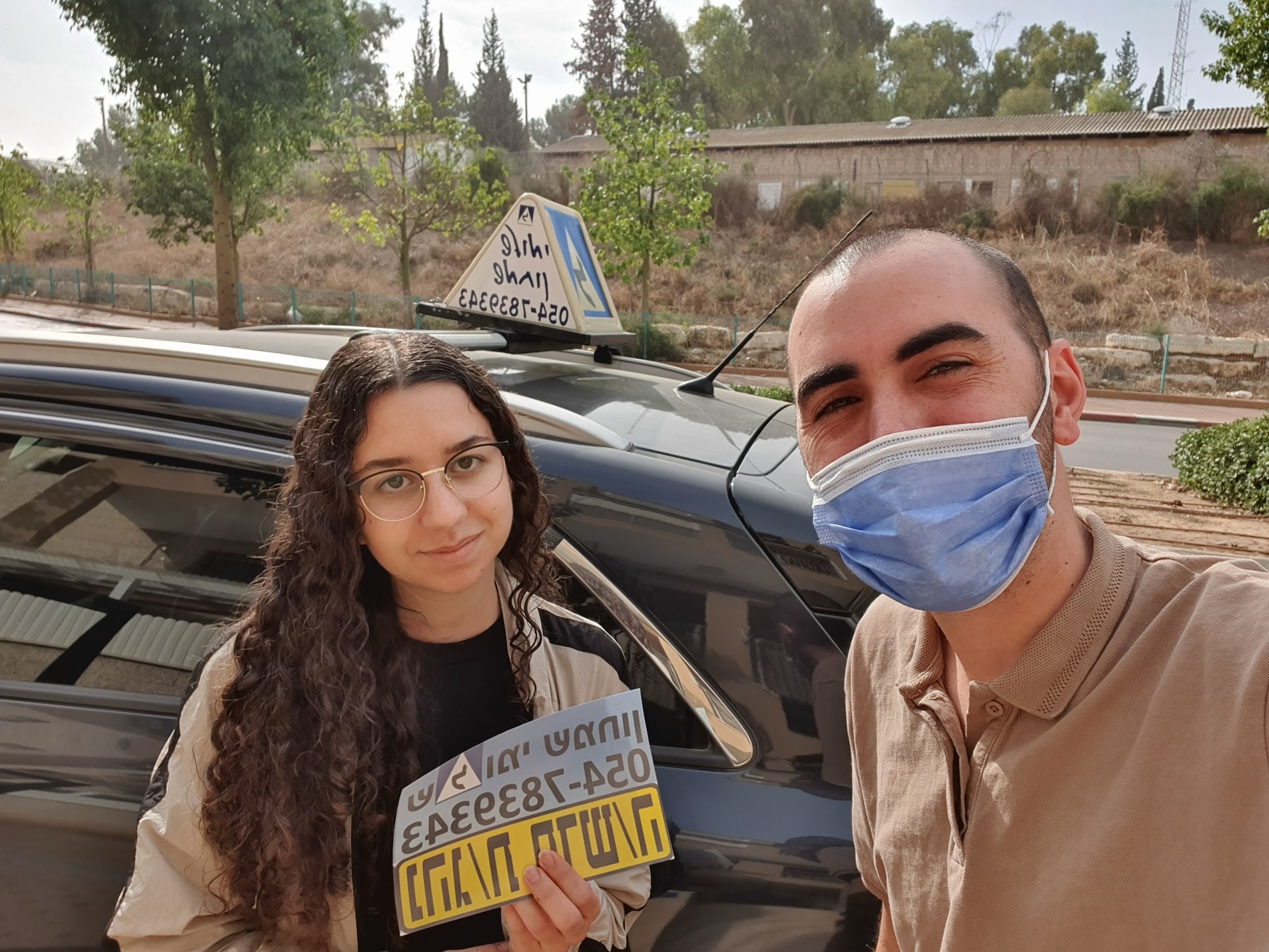 תלמיד עם שלומי שמחון, מורה נהיגה, מחזיק שלט "נהג חדש" לאחר המבחן – תמונה 62