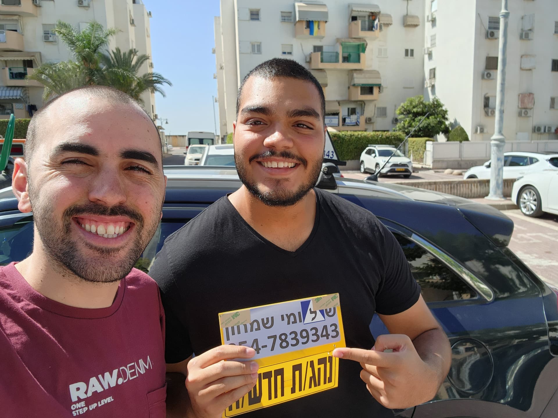 תלמיד עם שלומי שמחון, מורה נהיגה, מחזיק שלט "נהג חדש" לאחר המבחן – תמונה 30