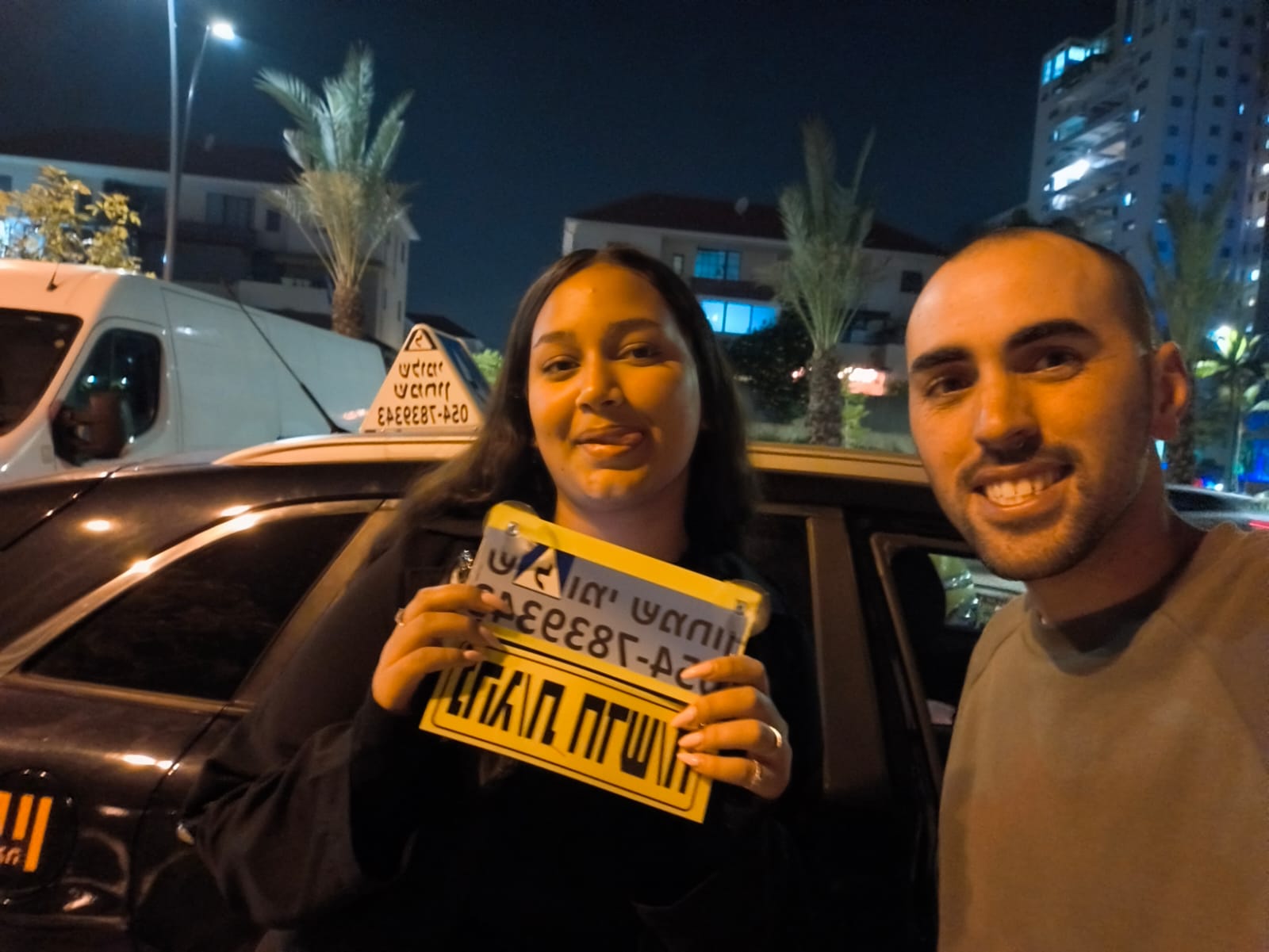 תלמיד עם שלומי שמחון, מורה נהיגה, מחזיק שלט "נהג חדש" לאחר המבחן – תמונה 49