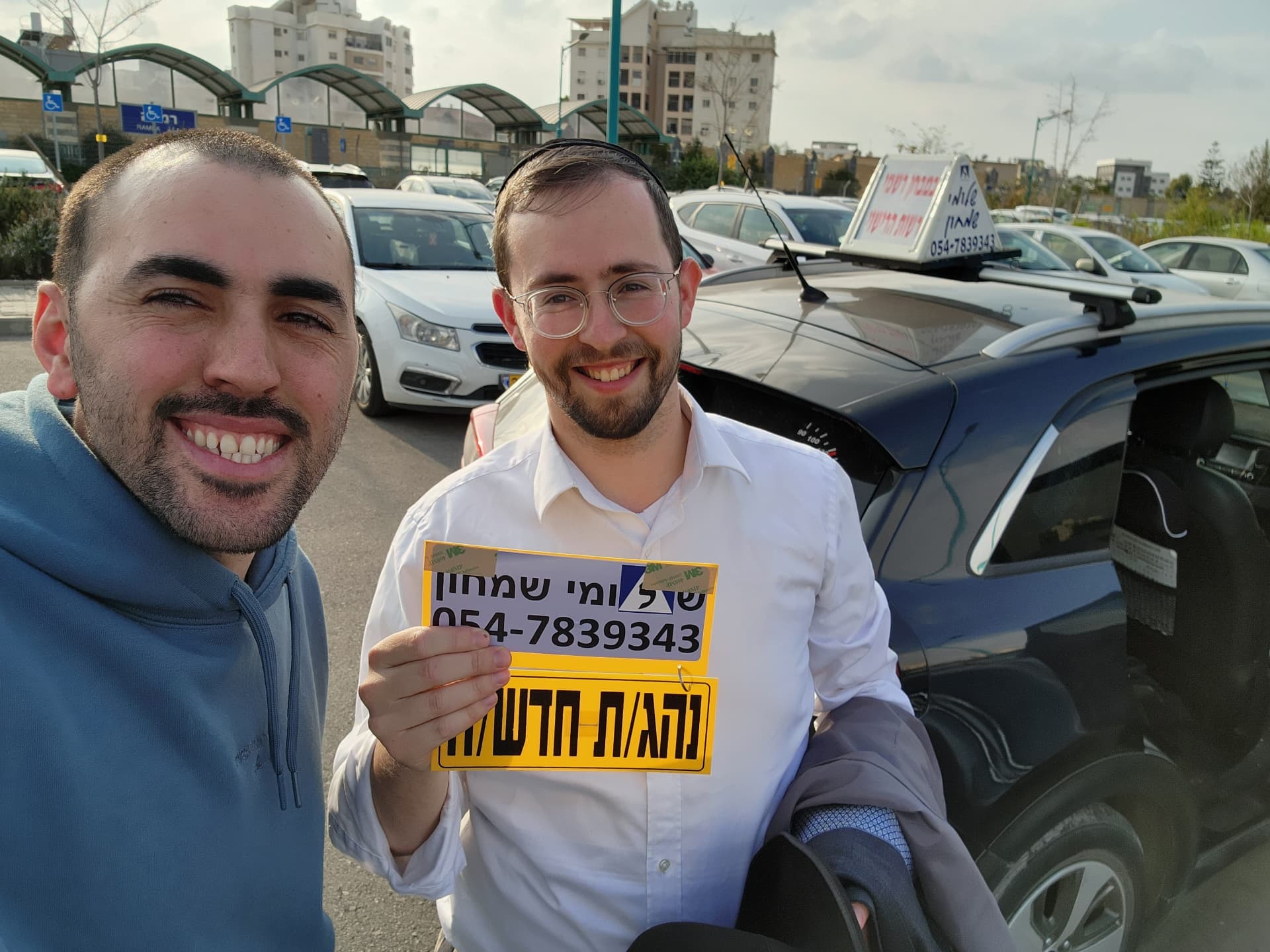 תלמיד עם שלומי שמחון, מורה נהיגה, מחזיק שלט "נהג חדש" לאחר המבחן – תמונה 46