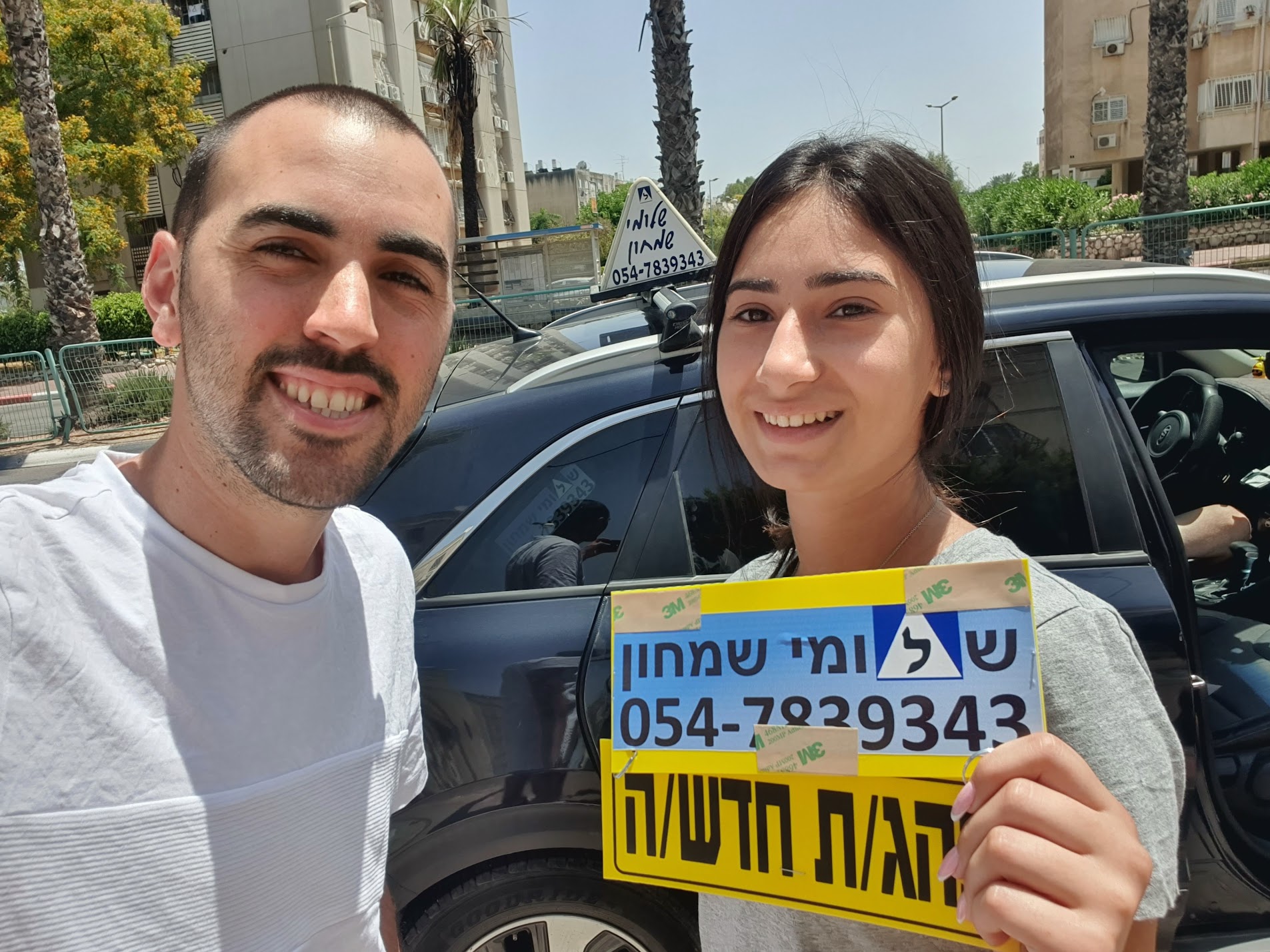 תלמיד עם שלומי שמחון, מורה נהיגה, מחזיק שלט "נהג חדש" לאחר המבחן – תמונה 51