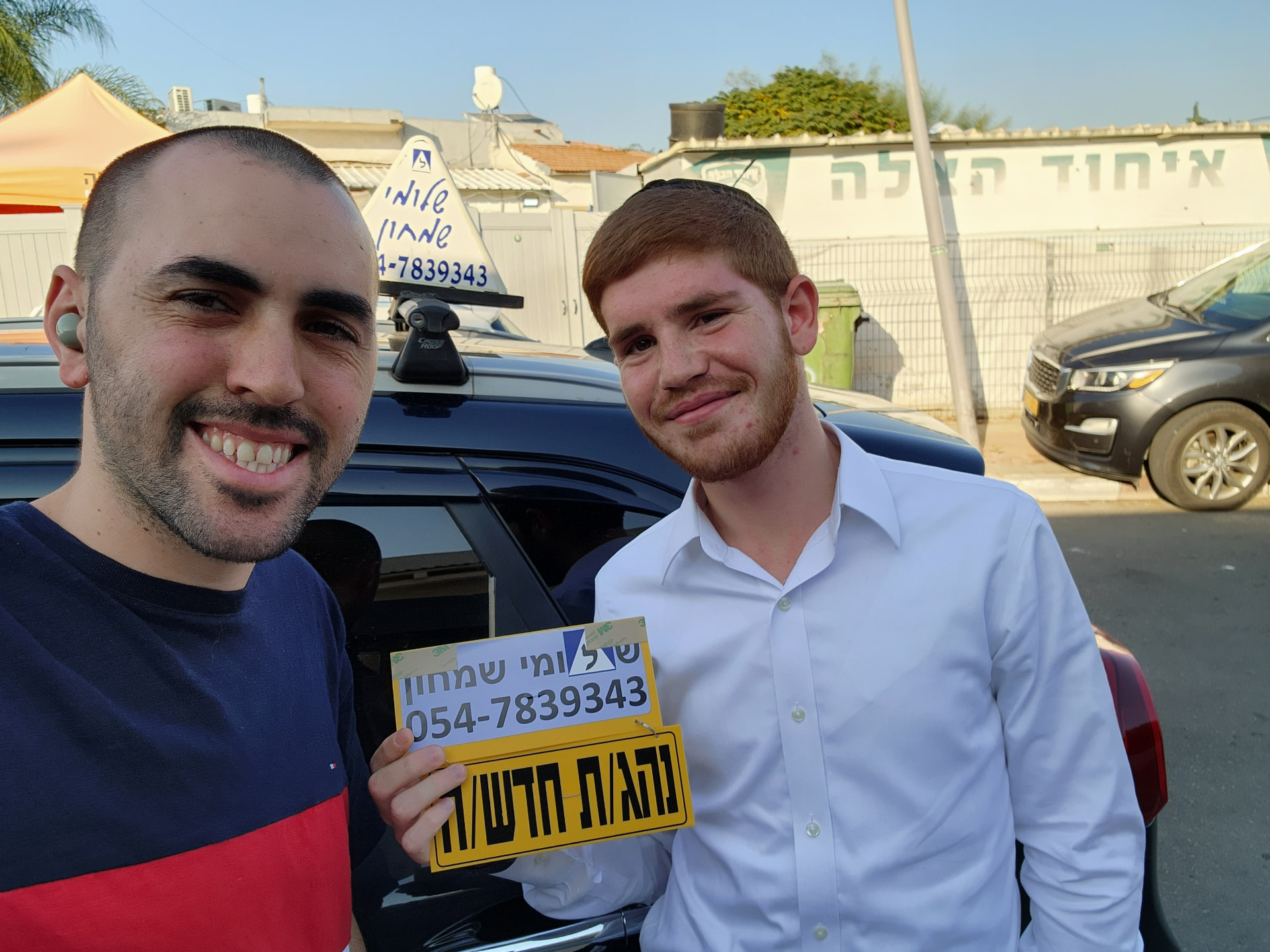 תלמיד עם שלומי שמחון, מורה נהיגה, מחזיק שלט "נהג חדש" לאחר המבחן – תמונה 23