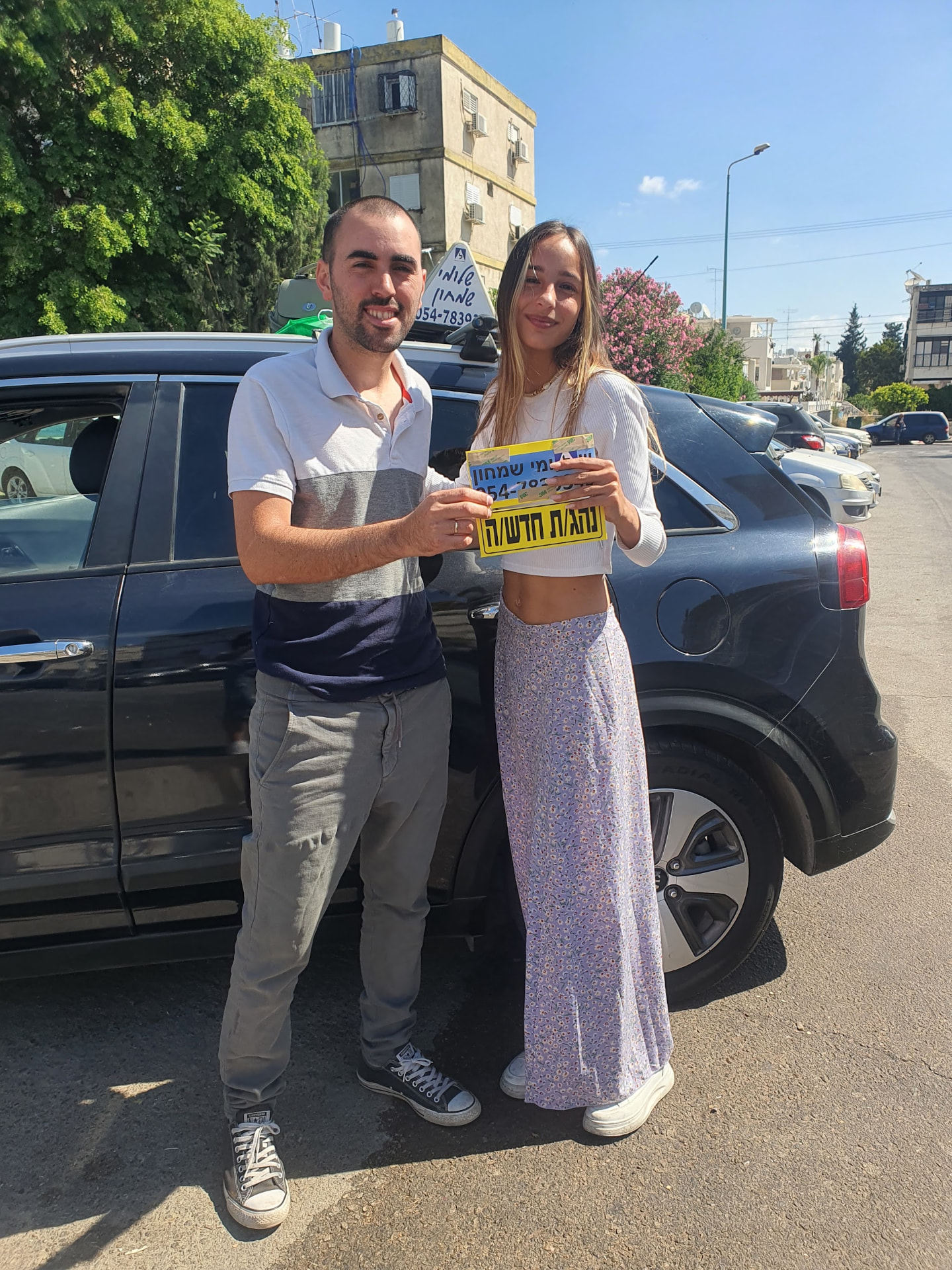 תלמיד עם שלומי שמחון, מורה נהיגה, מחזיק שלט "נהג חדש" לאחר המבחן – תמונה 2