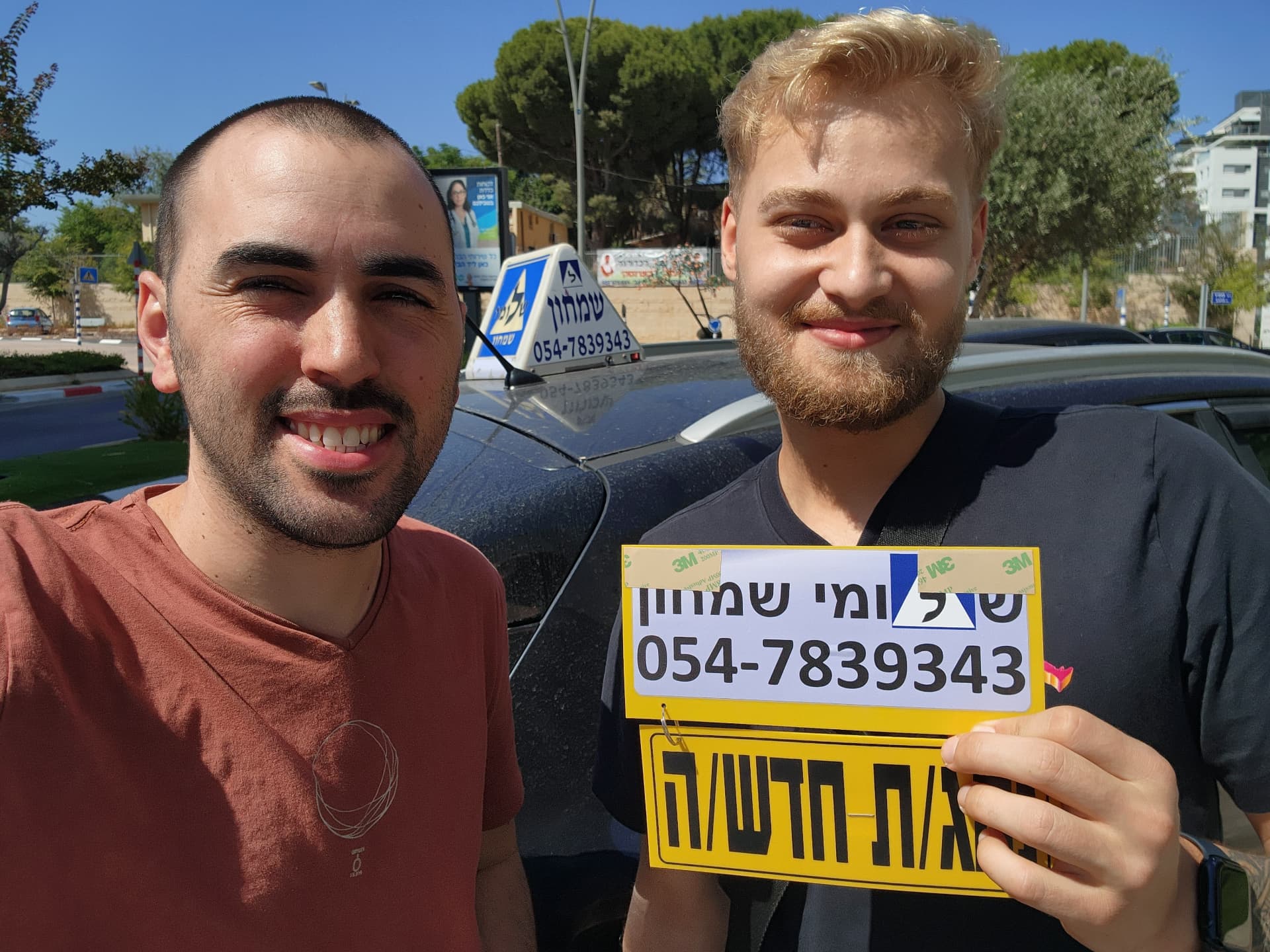 תלמיד עם שלומי שמחון, מורה נהיגה, מחזיק שלט "נהג חדש" לאחר המבחן – תמונה 33