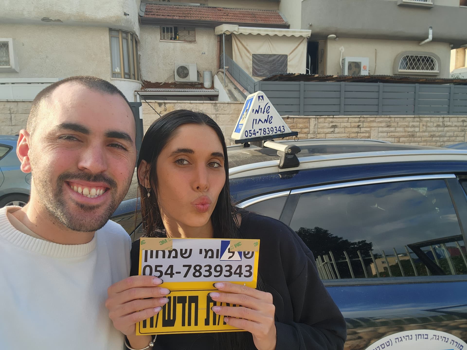 תלמיד עם שלומי שמחון, מורה נהיגה, מחזיק שלט "נהג חדש" לאחר המבחן – תמונה 21