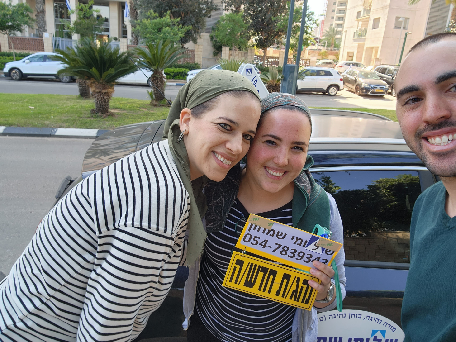 תלמיד עם שלומי שמחון, מורה נהיגה, מחזיק שלט "נהג חדש" לאחר המבחן – תמונה 9