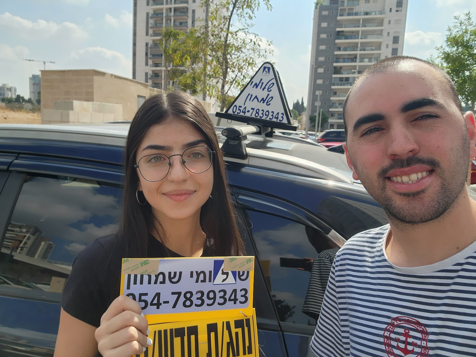 תלמיד עם שלומי שמחון, מורה נהיגה, מחזיק שלט "נהג חדש" לאחר המבחן – תמונה 3
