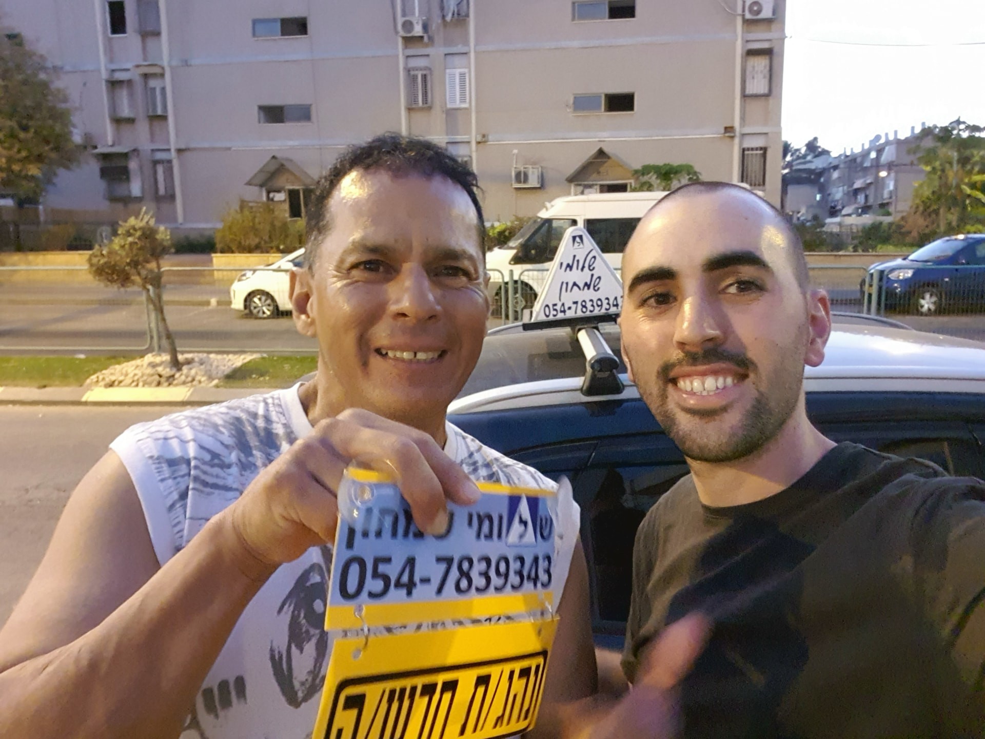 תלמיד עם שלומי שמחון, מורה נהיגה, מחזיק שלט "נהג חדש" לאחר המבחן – תמונה 41