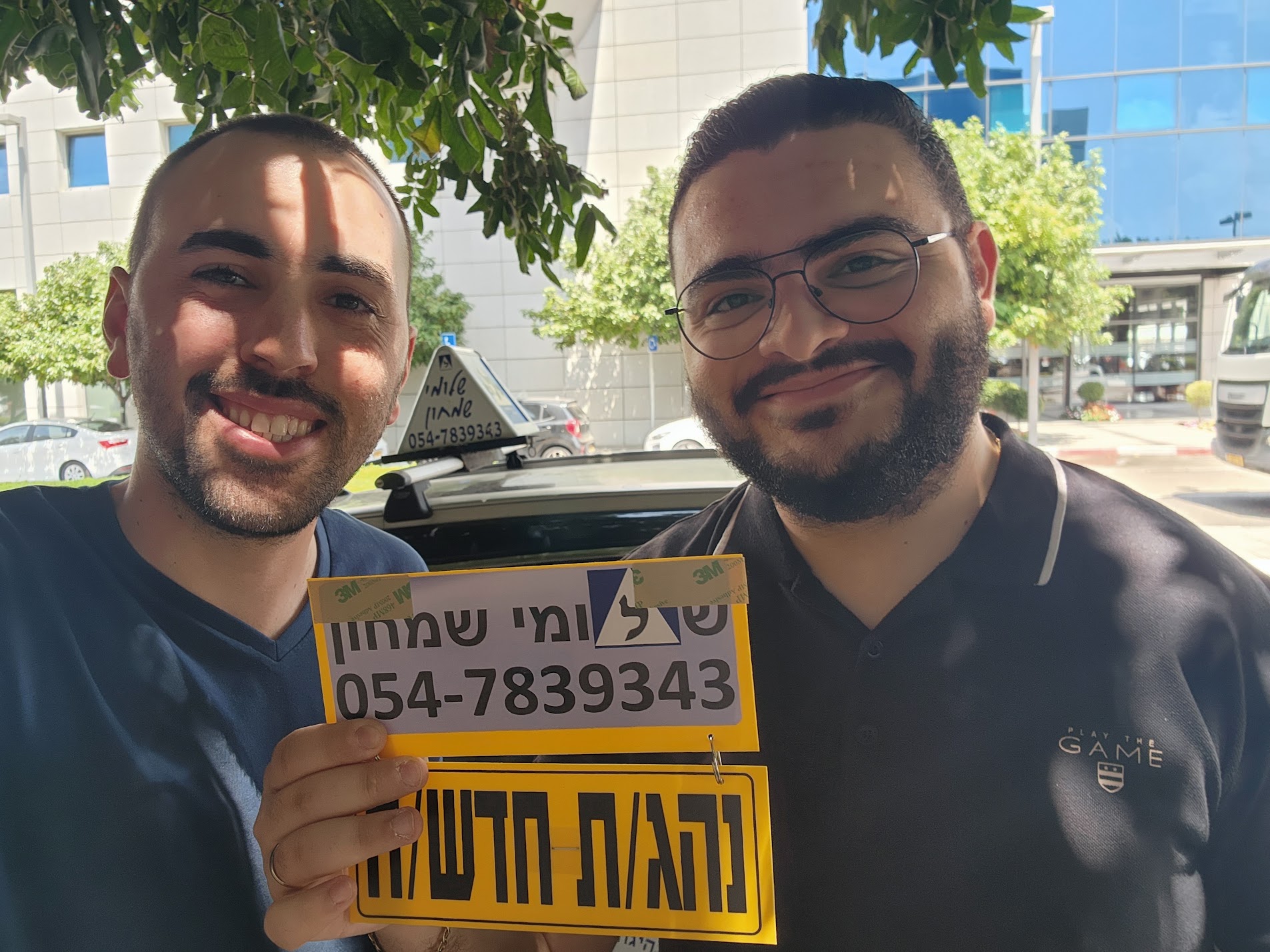 תלמיד עם שלומי שמחון, מורה נהיגה, מחזיק שלט "נהג חדש" לאחר המבחן – תמונה 50