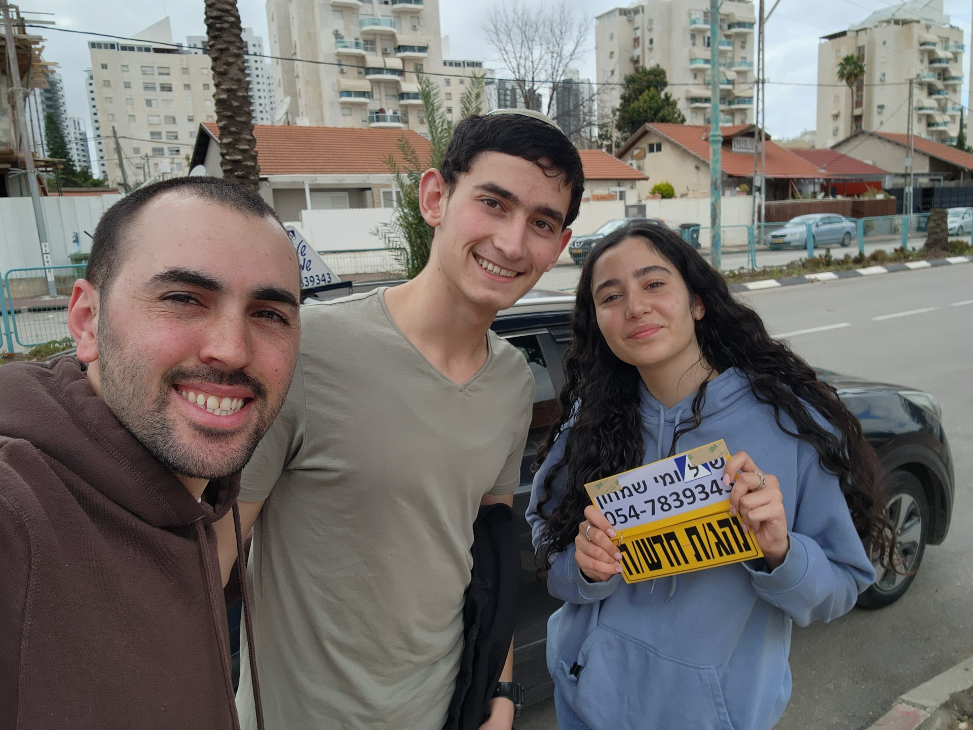 תלמיד עם שלומי שמחון, מורה נהיגה, מחזיק שלט "נהג חדש" לאחר המבחן – תמונה 7