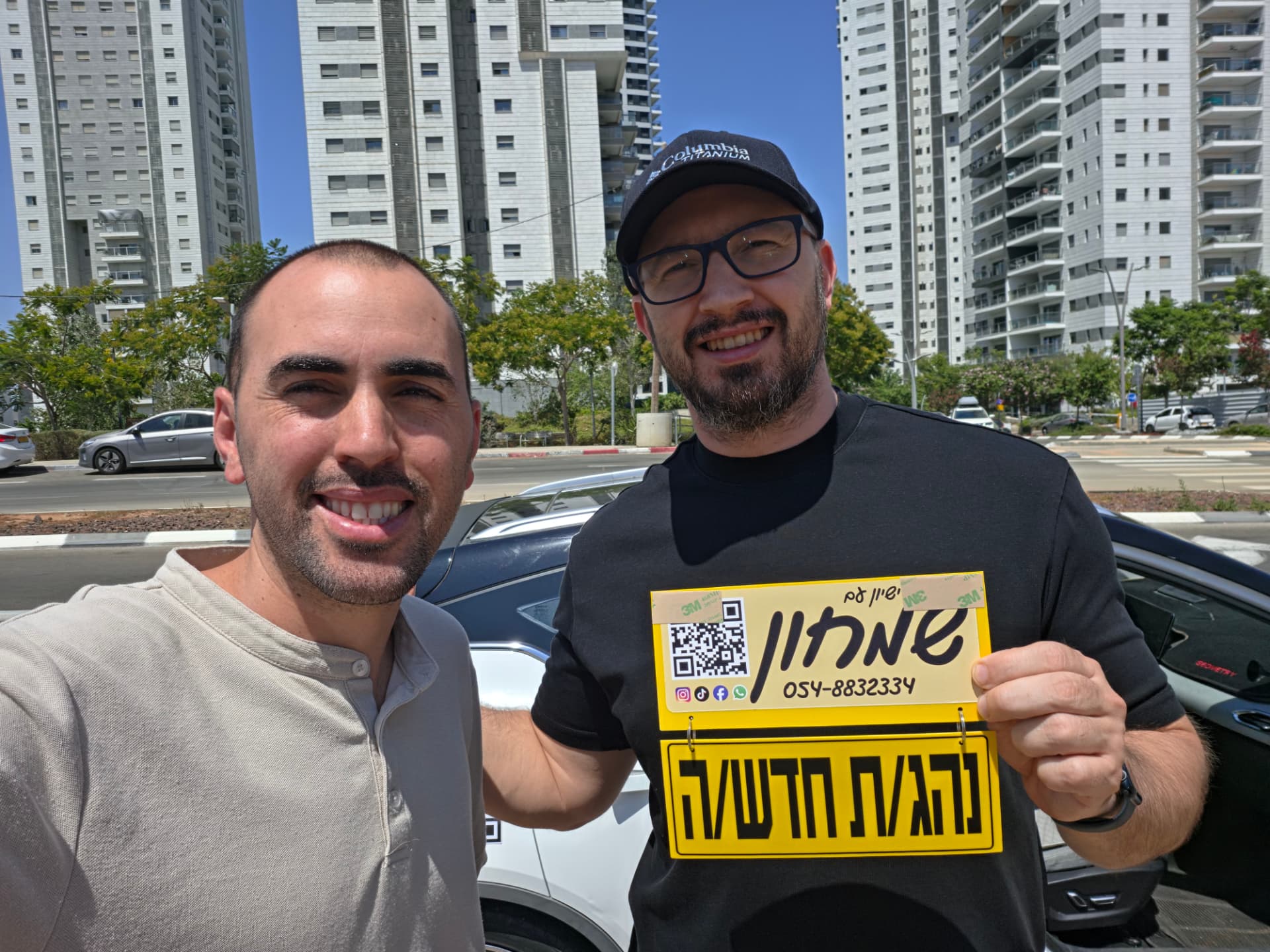 תלמיד עם שלומי שמחון, מורה נהיגה, מחזיק שלט "נהג חדש" לאחר המבחן – תמונה 1