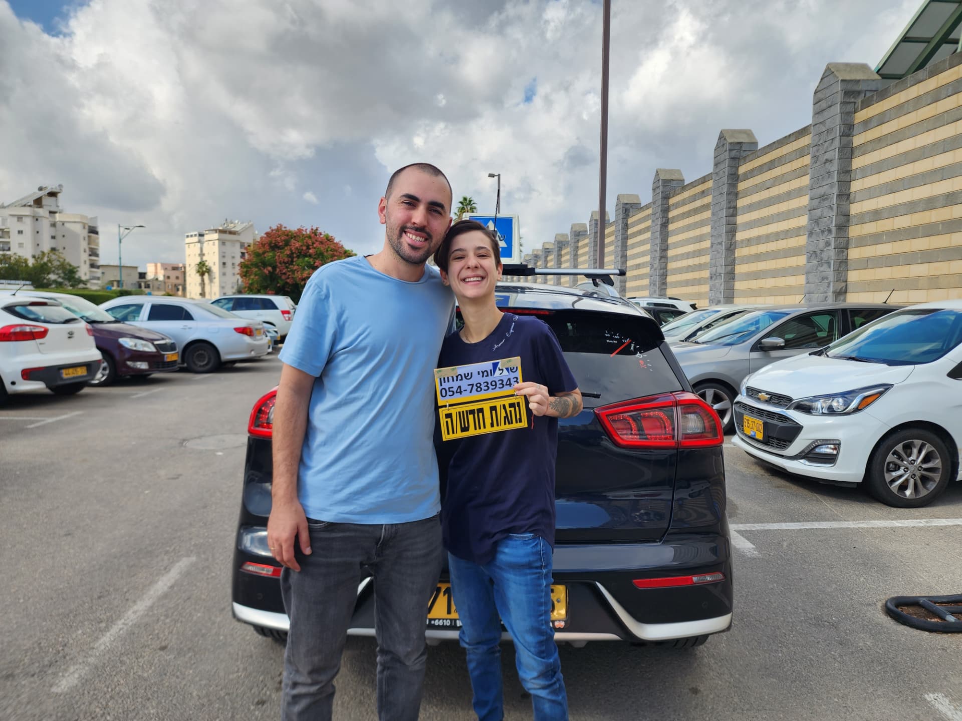 תלמיד עם שלומי שמחון, מורה נהיגה, מחזיק שלט "נהג חדש" לאחר המבחן – תמונה 29