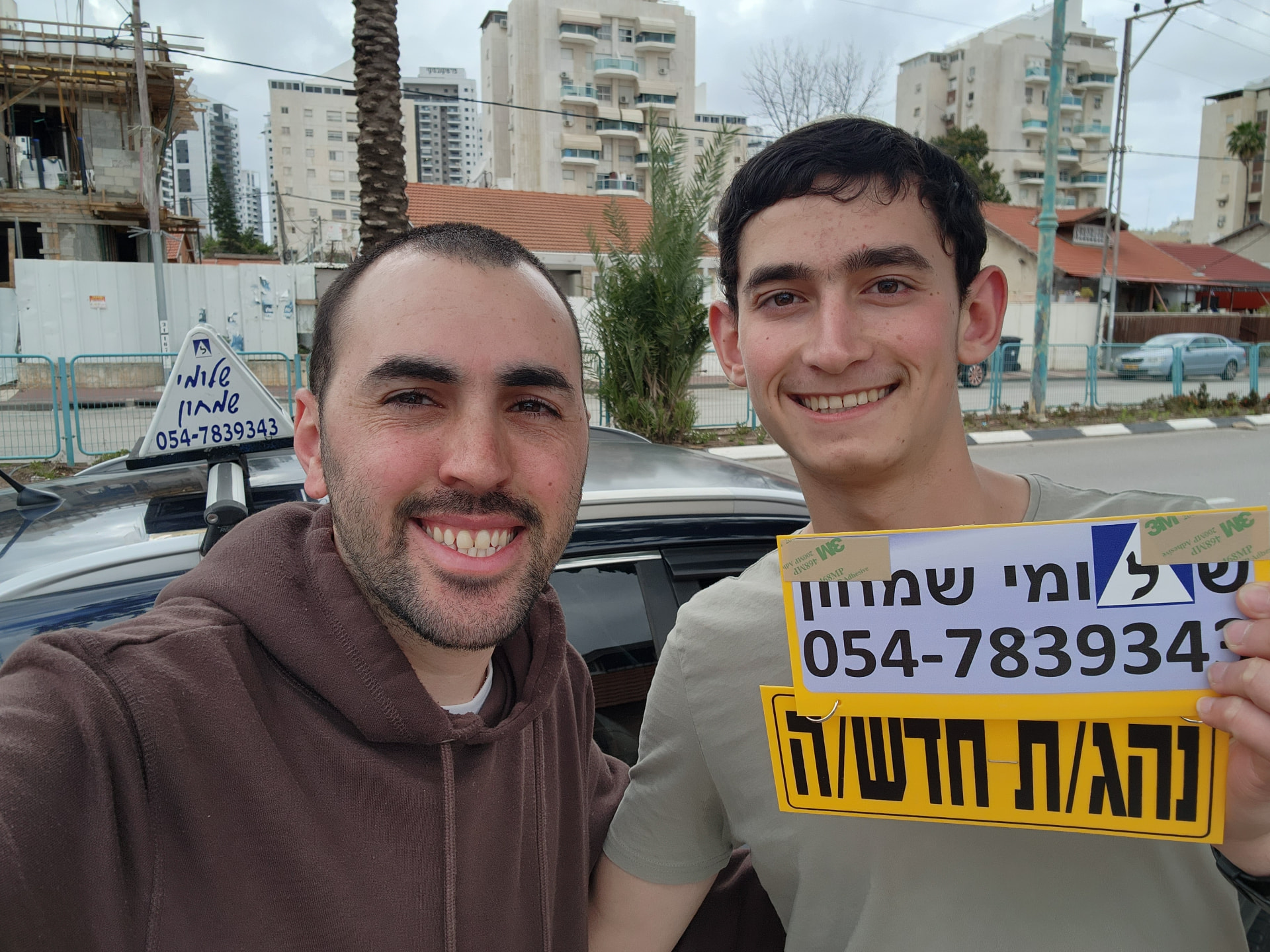 תלמיד עם שלומי שמחון, מורה נהיגה, מחזיק שלט "נהג חדש" לאחר המבחן – תמונה 19
