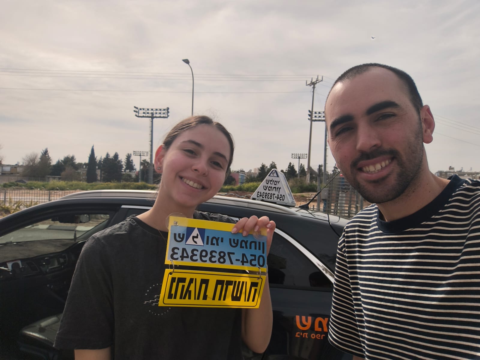 תלמיד עם שלומי שמחון, מורה נהיגה, מחזיק שלט "נהג חדש" לאחר המבחן – תמונה 43