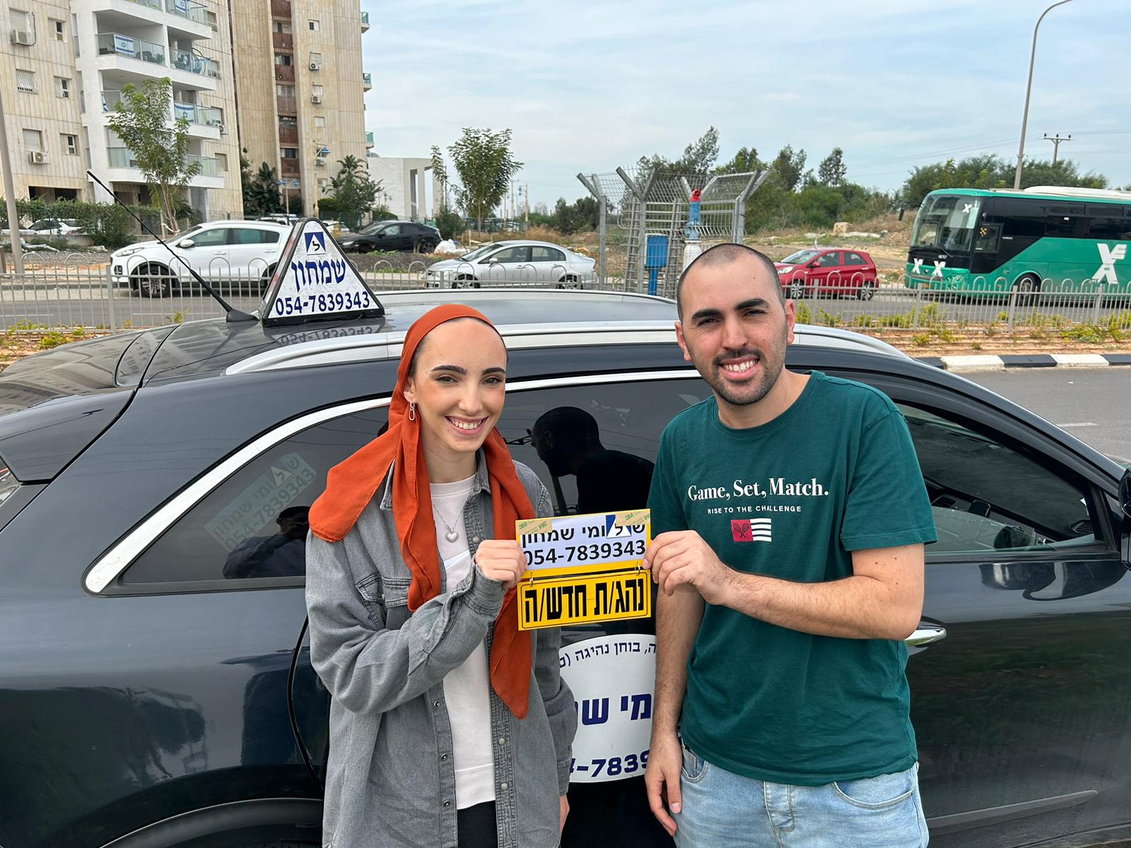 תלמיד עם שלומי שמחון, מורה נהיגה, מחזיק שלט "נהג חדש" לאחר המבחן – תמונה 48