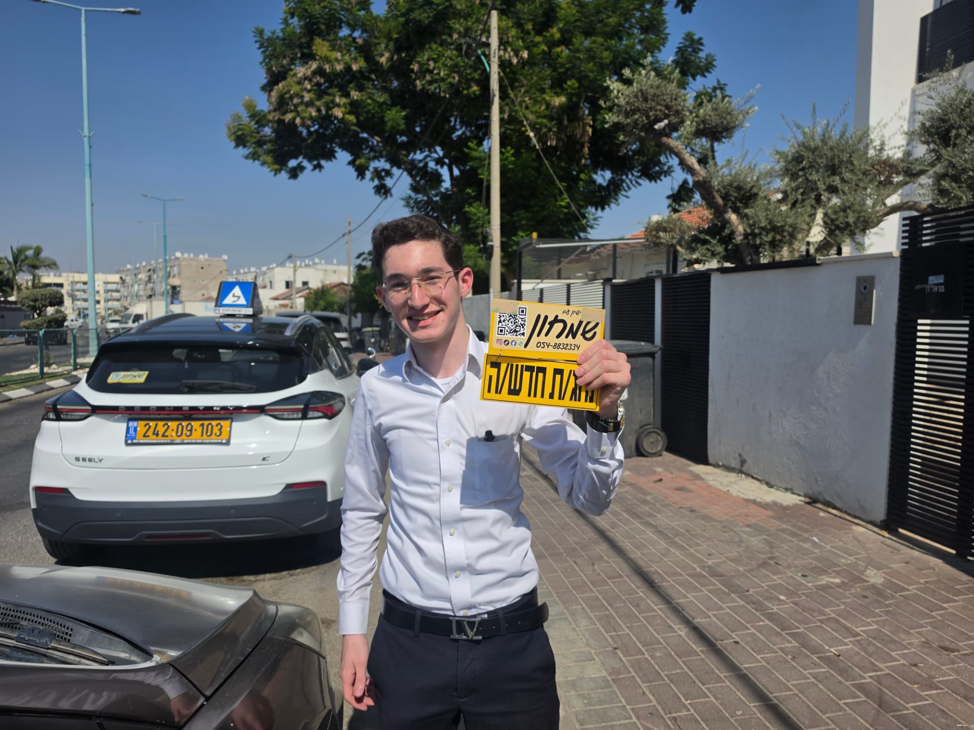 תלמיד עם שלומי שמחון, מורה נהיגה, מחזיק שלט "נהג חדש" לאחר המבחן – תמונה 6
