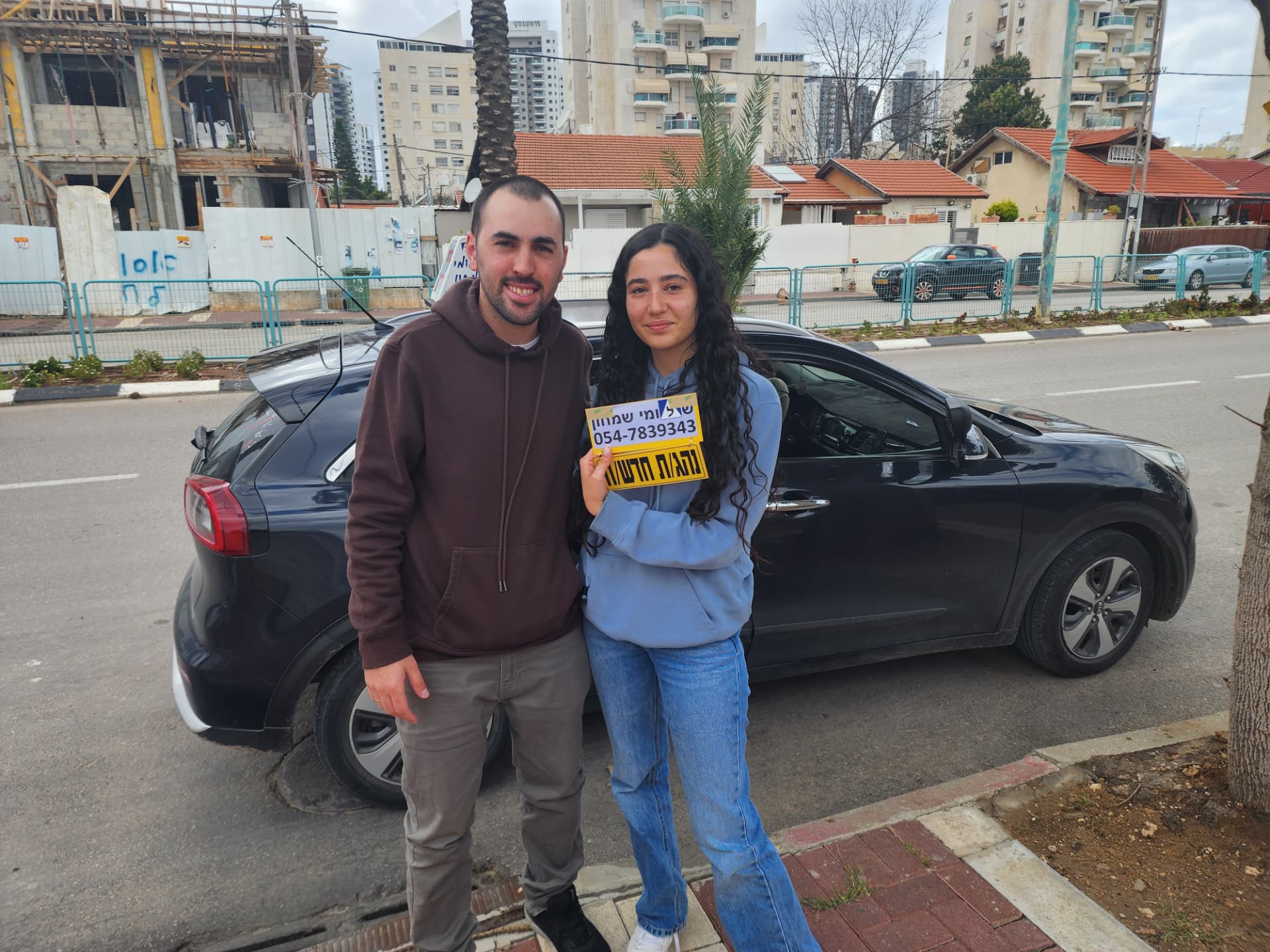 תלמיד עם שלומי שמחון, מורה נהיגה, מחזיק שלט "נהג חדש" לאחר המבחן – תמונה 14