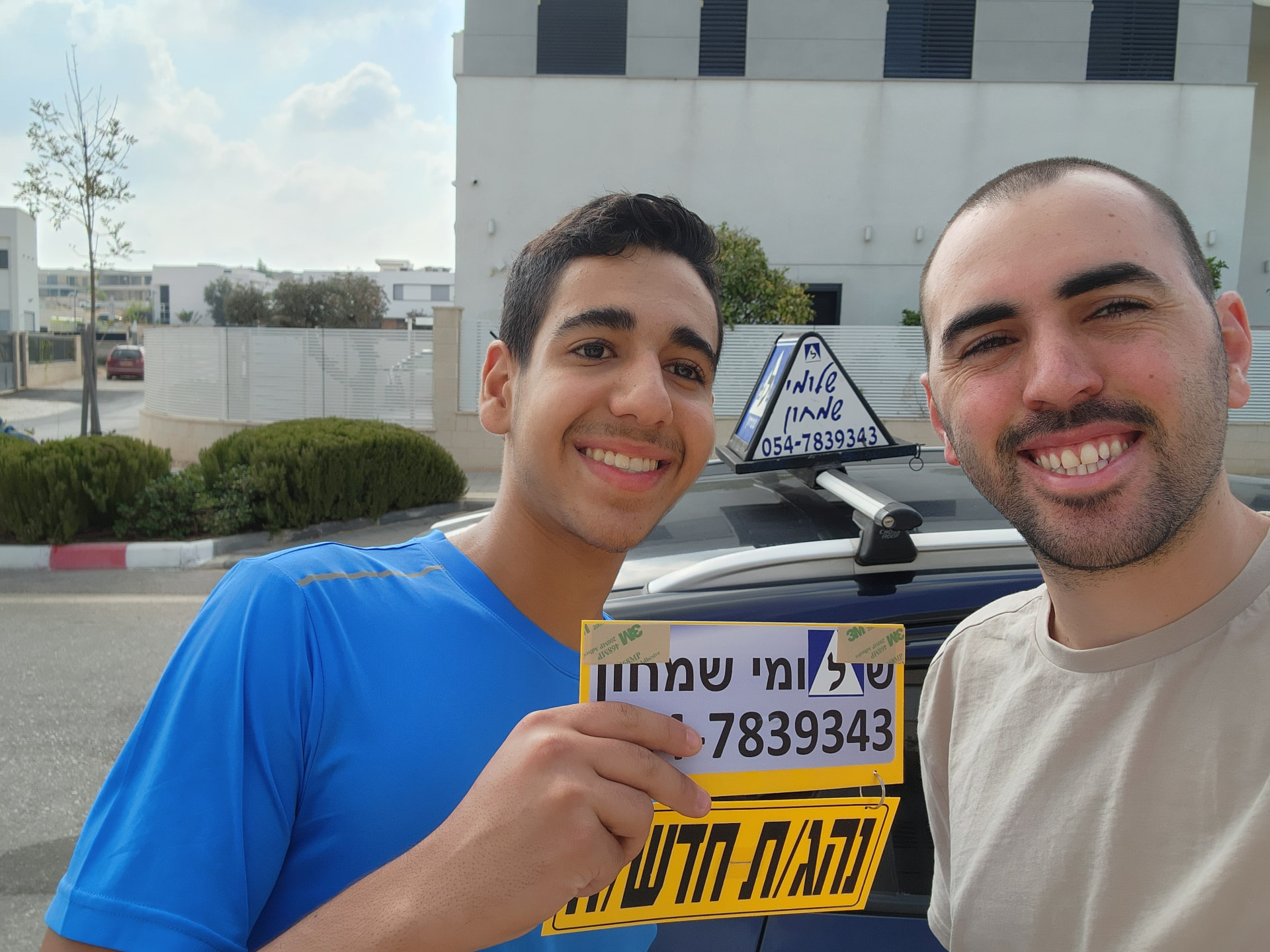 תלמיד עם שלומי שמחון, מורה נהיגה, מחזיק שלט "נהג חדש" לאחר המבחן – תמונה 11