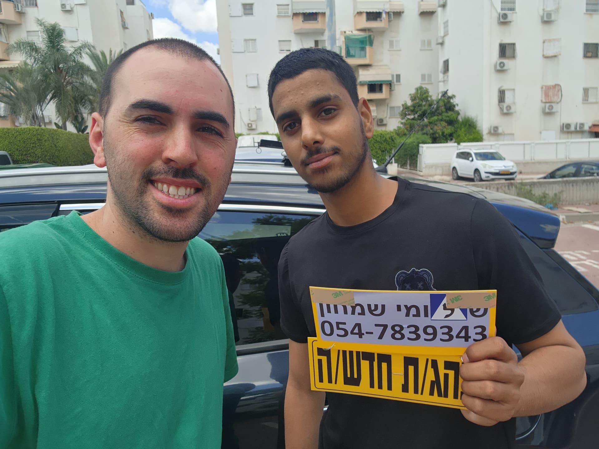 תלמיד עם שלומי שמחון, מורה נהיגה, מחזיק שלט "נהג חדש" לאחר המבחן – תמונה 25